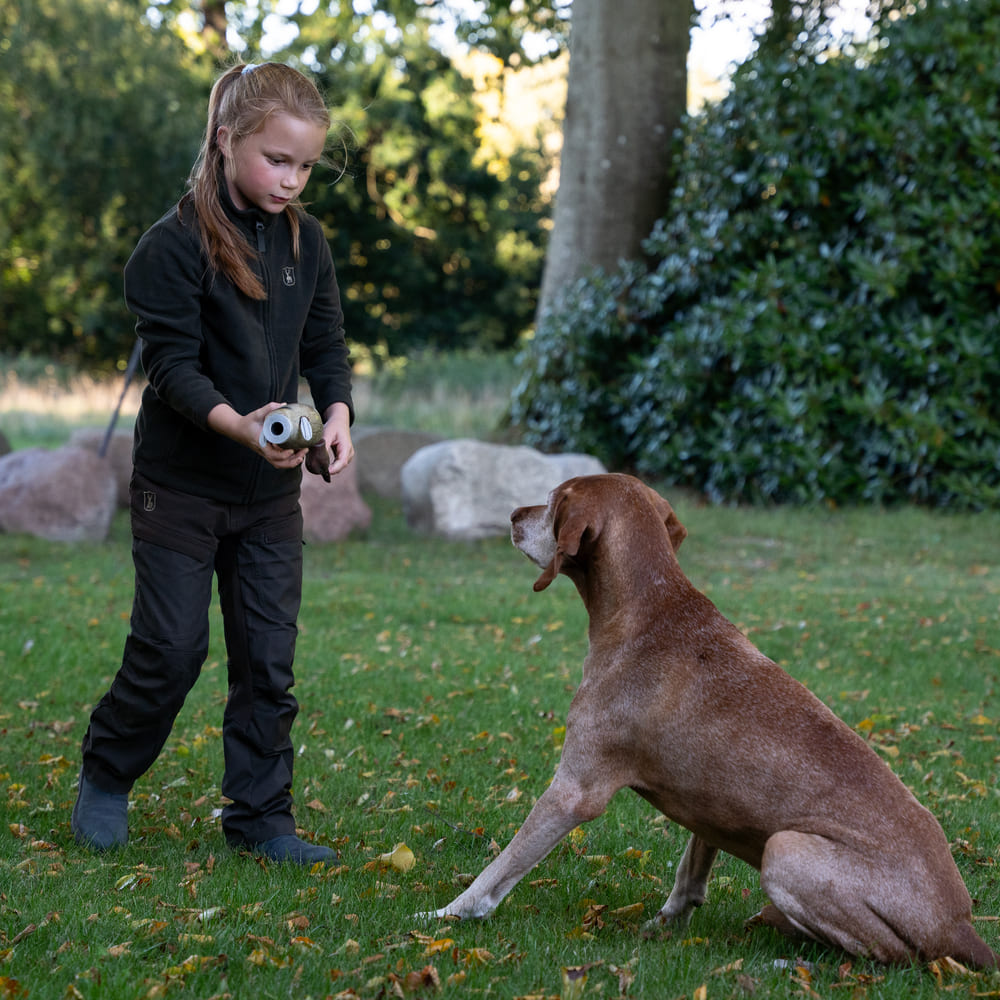 Kind mit Deerhunter Youth Atlas Light Fleecejacke spielt mit Jagdhund im Garten und Outdoor-Bereich