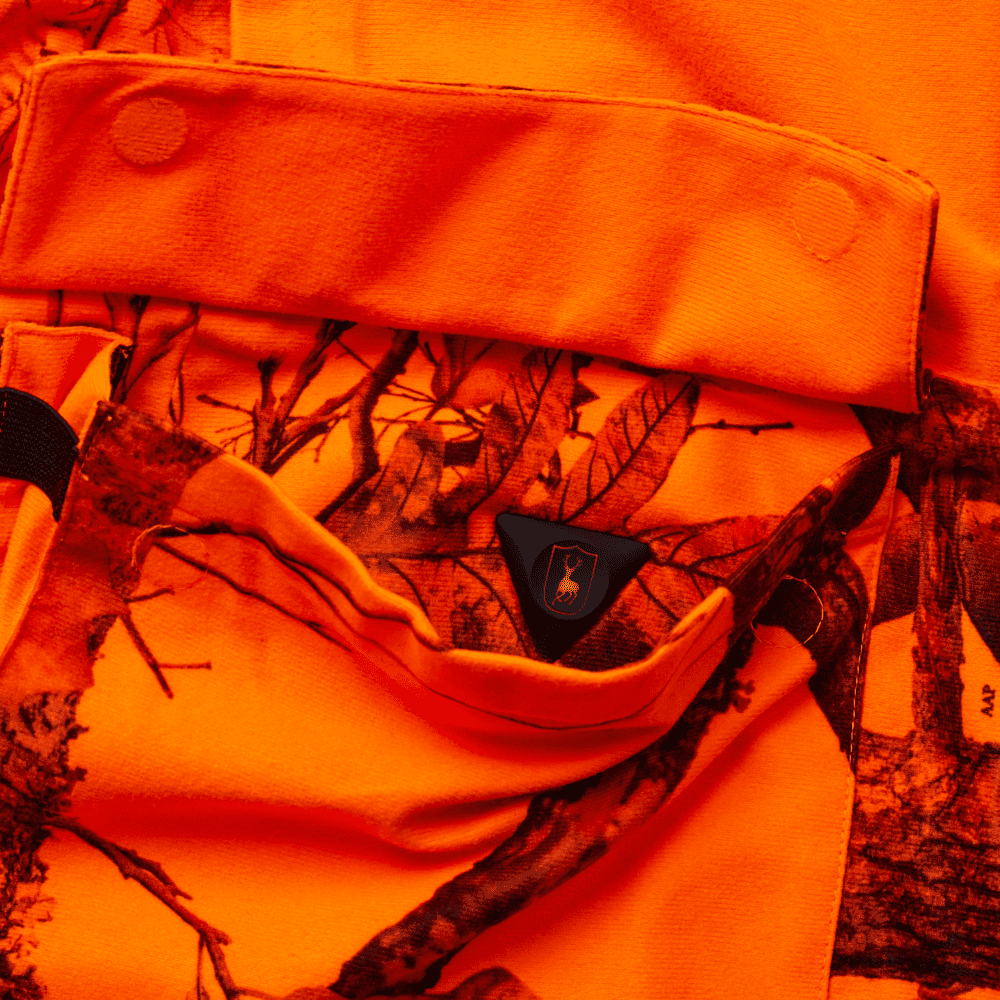 Detailaufnahme einer Tasche der Deerhunter Jagdjacke in orange Tarnoptik mit Klappe und Druckknopf, praktische Jagdbekleidung mit sicherem Stauraum für Outdoor und Jagd