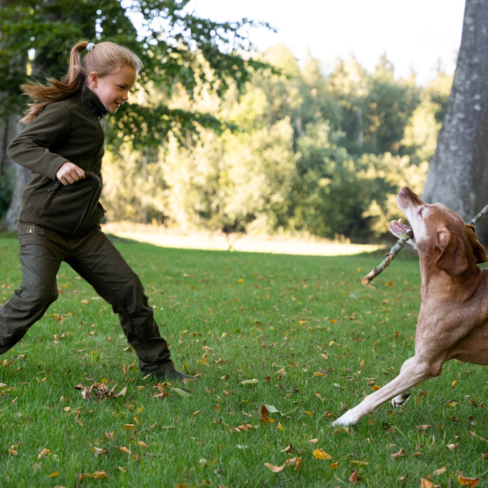 Kind trägt Deerhunter Youth Atlas Light Fleecejacke beim Hundetraining und Spielen im Freien